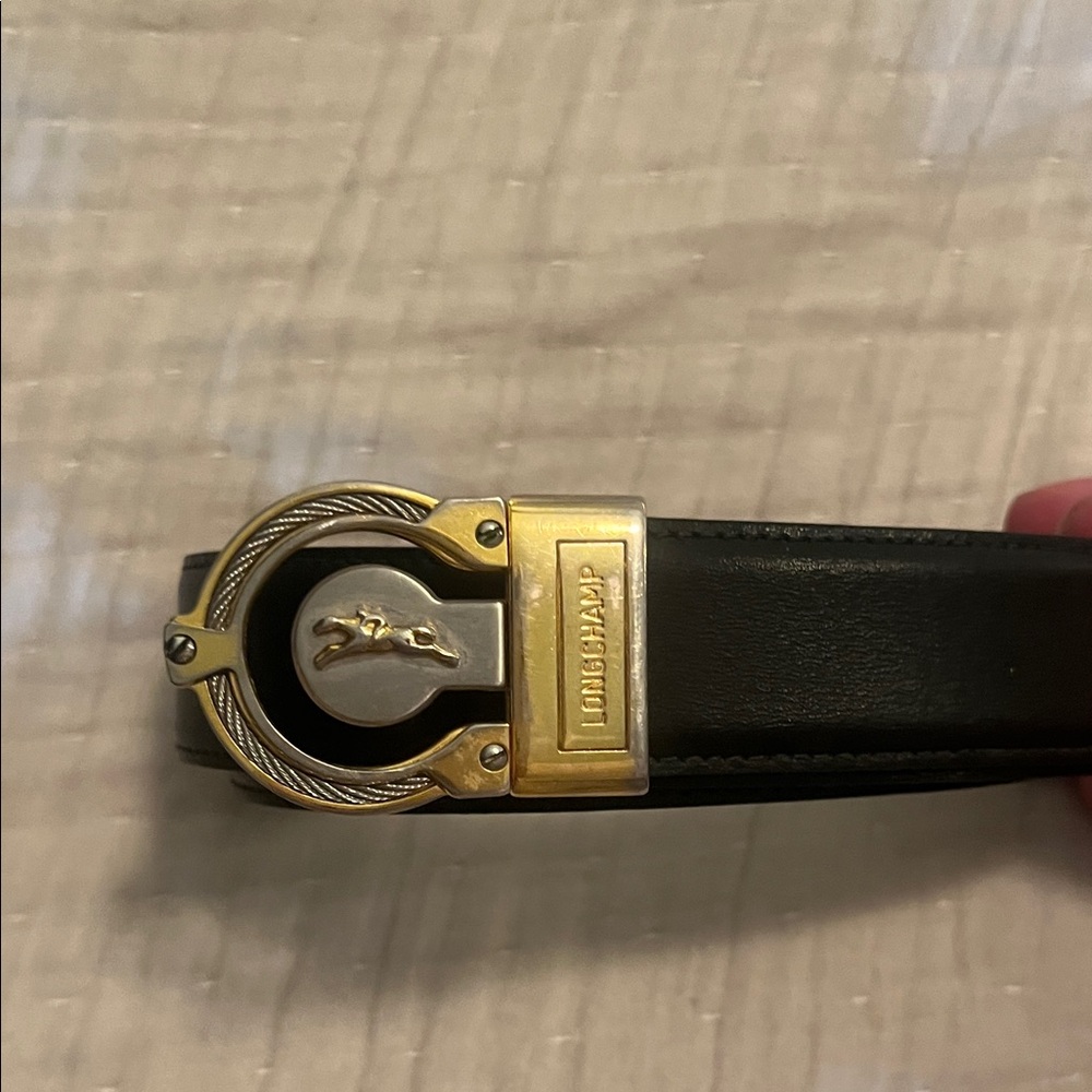 Unisex Longchamp black leather belt with silver and gold buckle detail.